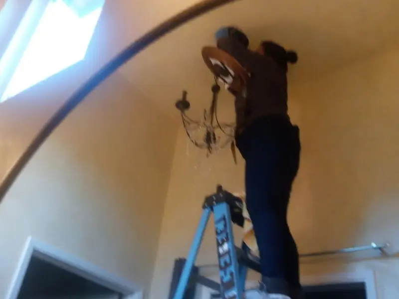 Electrician installing a chandelier in a Arlington residence